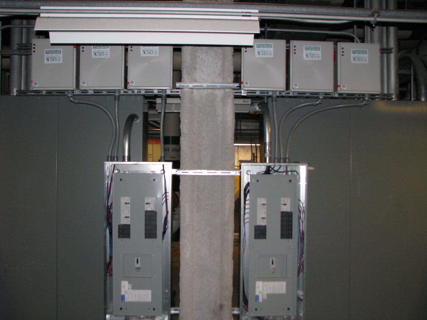 Two electrical panels mounted on a central column in an industrial setting.