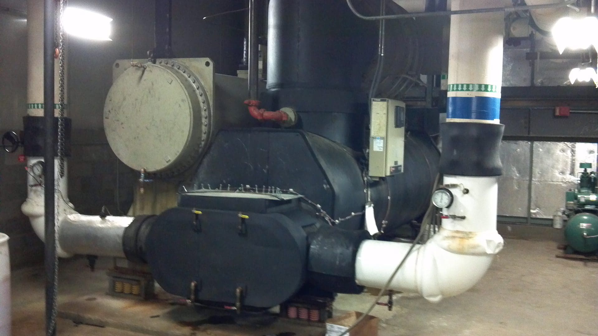 Industrial furnace with pipes and control panel in a mechanical room.