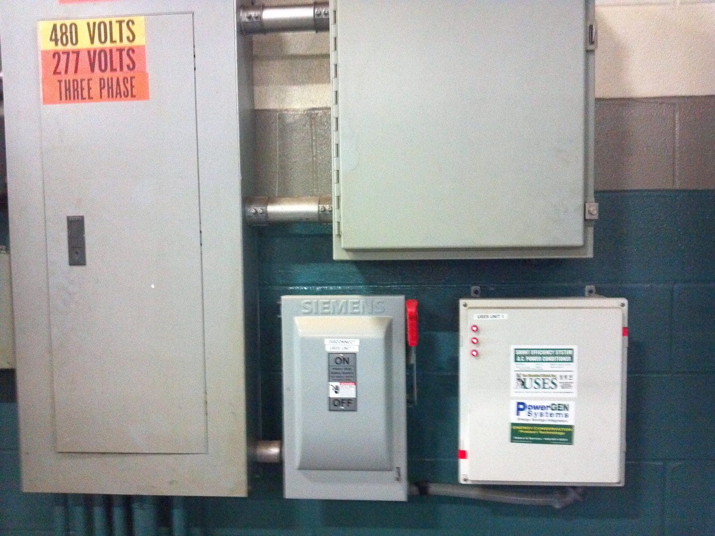 Electrical panels and circuit breakers mounted on a wall in an industrial setting.