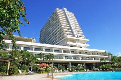 Modern hotel with a pool under clear blue sky.