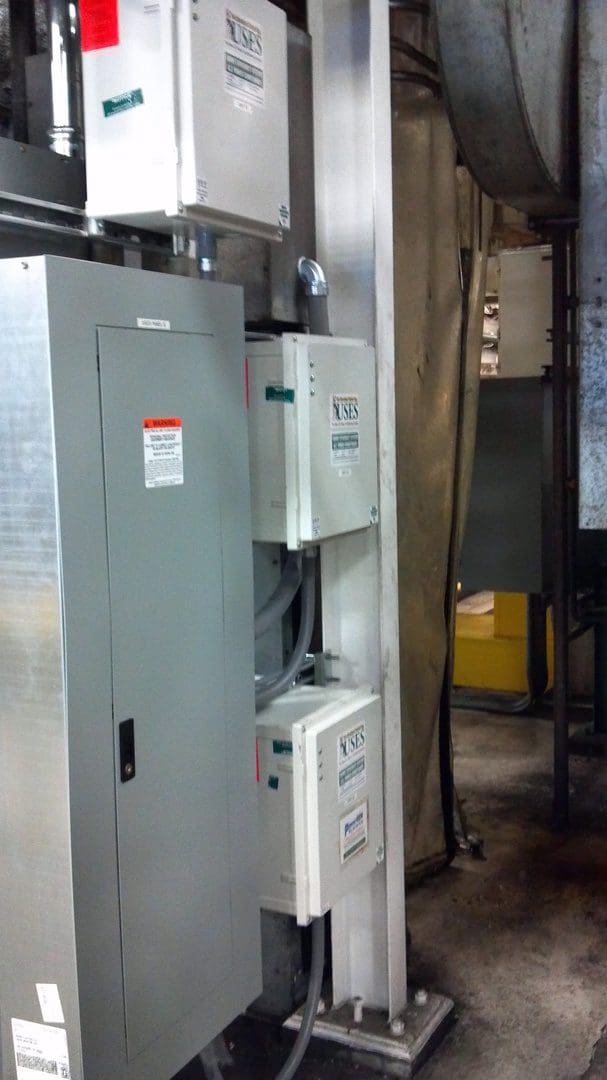 Industrial electrical control panels with warning labels in a utility room.