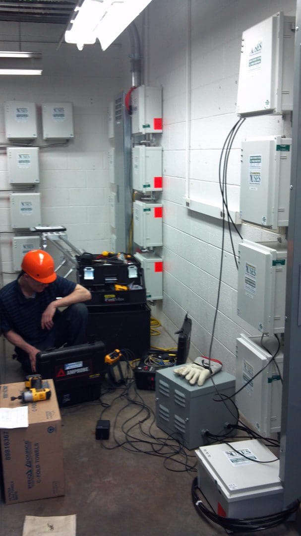 Technician working on electrical equipment in a utility room.