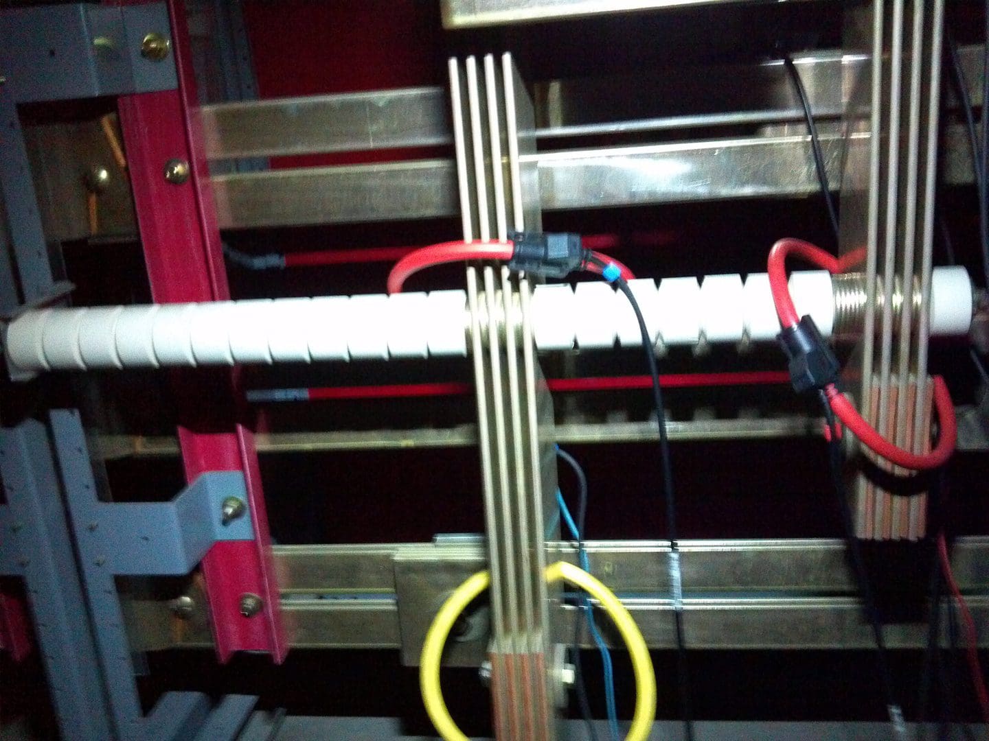 Close-up of electrical wiring and conduit pipes inside a panel.